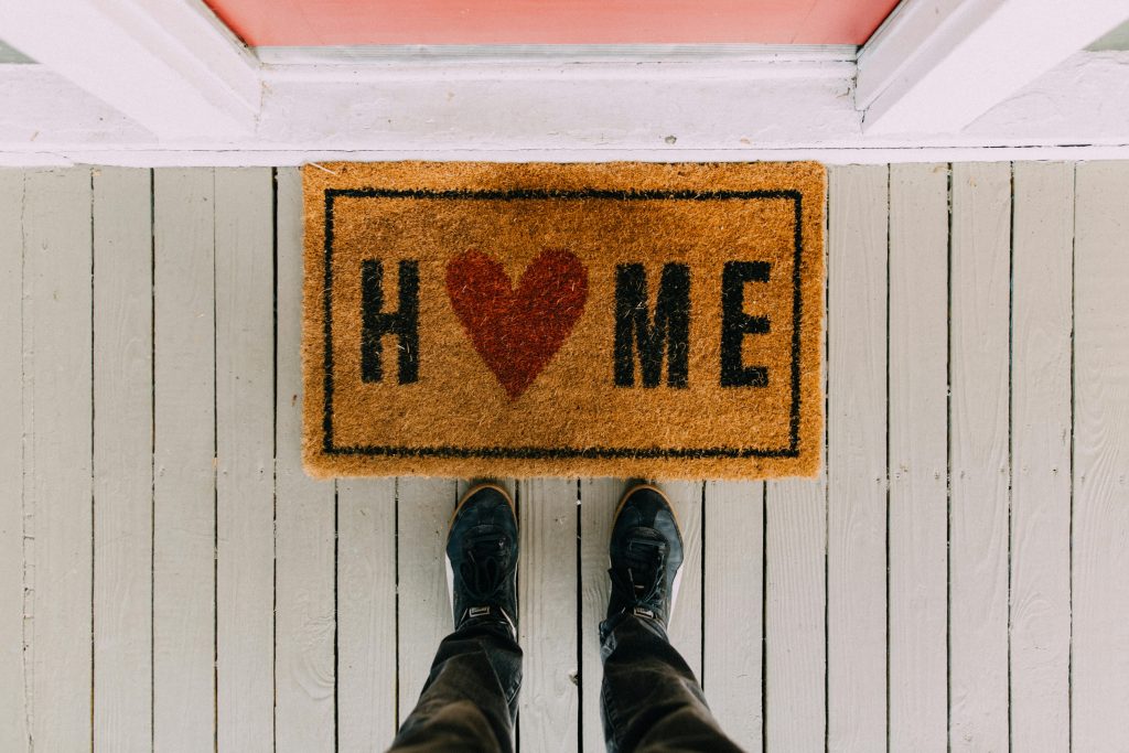 Paillasson avec marqué "Home" (maison) et des pieds d'homme devant.